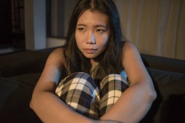 Genç, üzgün ve depresif Asyalı bir kadının dramatik ev hayatı portresi. Acı içinde uzanmış, kanepede ağlıyor. Stresli ve endişeli depresyonda. 