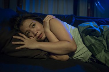 Oturma odasındaki kanepede acı içinde kıvranan genç, üzgün ve depresif bir Japon kadının dramatik bir ev hayatı portresi. Üzüntü ve endişe dolu bir depresyon içinde.