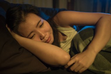 Oturma odasındaki kanepede acı içinde kıvranan genç, üzgün ve depresif bir Japon kadının dramatik bir ev hayatı portresi. Üzüntü ve endişe dolu bir depresyon içinde.