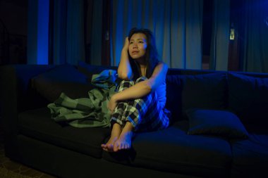 Genç, üzgün ve depresif Asyalı bir kadının dramatik ev hayatı portresi oturma odasındaki kanepede yatıyor kırık bir kalp depresyon ve anksiyete acısı çekiyor.