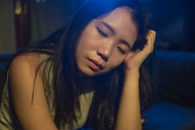 Genç, üzgün ve depresif Asyalı bir kadın. Karanlıkta gözyaşları içinde acı içinde ağlıyor. Endişeli ve çaresiz hissediyor.