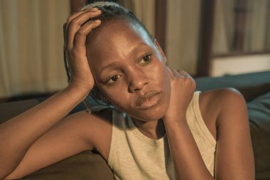 Depresyonda olan genç bir Afro-Amerikalı kadın. Üzgün ve depresif bir genç kız. Kanepede acı çekiyor.