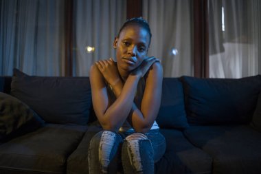 Milenyum kuşağı Afro-Amerikan kızı geceleri depresyona giriyor. Genç, üzgün ve depresif siyah kadın düşünceli ve endişeli bir şekilde kanepeye oturuyor. Acı ve korku içinde. 
