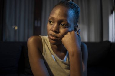 Milenyum kuşağı Afro-Amerikan kızı geceleri depresyona giriyor. Genç, üzgün ve depresif siyah kadın düşünceli ve endişeli bir şekilde kanepeye oturuyor. Acı ve korku içinde. 