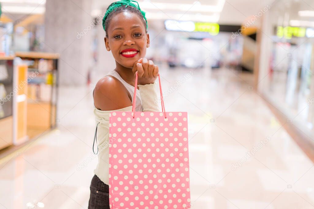 young happy and beautiful afro American girl at buying shopping mall - lifestyle portrait of millennial black girl enjoying looking  clothing at beauty fashion store playful and excite