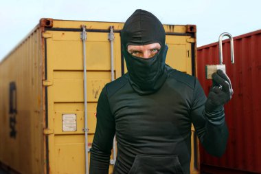 İş yerinde hırsız var. Kar maskeli bir suçlu nakliye alanında kilit kilidini açmış soygun ve suç kavramında depolama konteynerlerinde kırıyor.