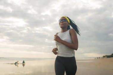 Sahilde koşan Afro-Amerikalı kadın. Genç, çekici ve atletik siyah kız. Açık havada antrenman yapıyor.