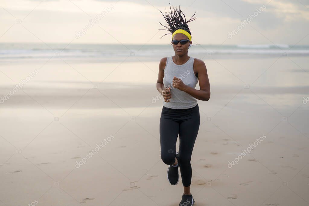 african American woman running on the beach - young attractive and athletic black girl training outdoors doing jogging workout at the sea in fitness and healthy lifestyle concept