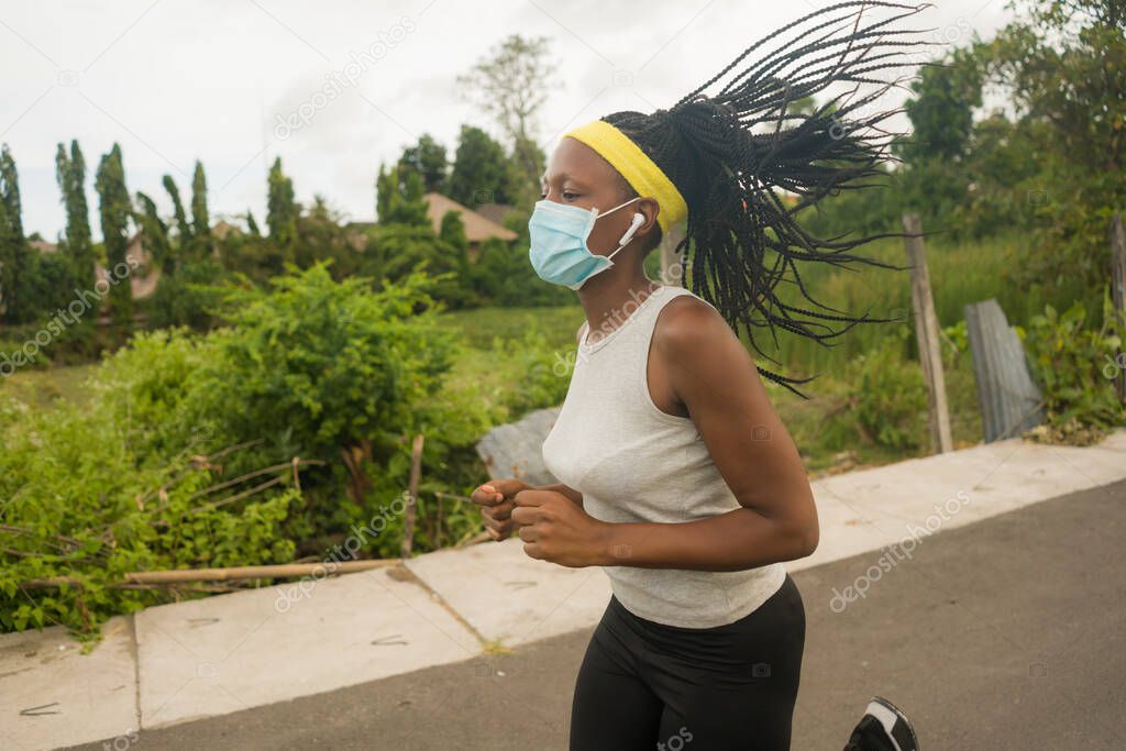 post quarantine runner girl enjoying outdoors workout - young attractive and fit black afro American woman running wearing face mask in new normal sport practice concept and healthy lifestyle