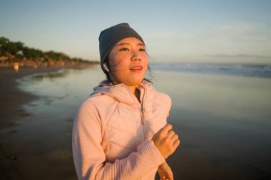 Sahilde koşan Asyalı bir kız. Genç, çekici ve mutlu Koreli bir kadın. Güzel plajda koşuyor.