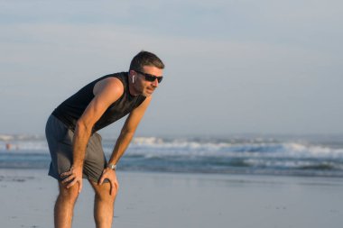 Yaz koşusu. Genç, çekici ve formda bir koşucu. Güzel bir sahilde antrenman yapıyor.