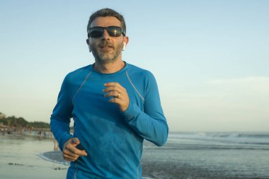 Açık hava koşusu antrenmanı. Genç çekici ve atletik koşucu. Yaz aylarında güzel plajlarda koşuyor. 