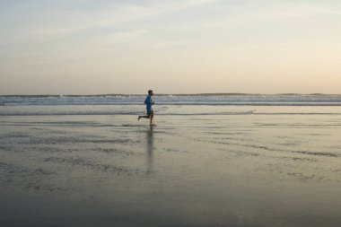 Açık hava koşusu antrenmanı. Genç çekici ve atletik koşucu. Yaz aylarında güzel plajlarda koşuyor. 