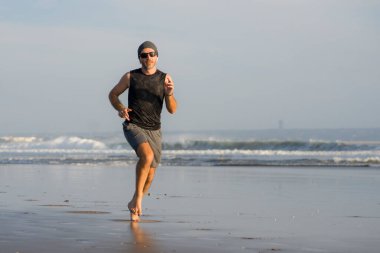 Açık hava koşusu antrenmanı. Genç çekici ve atletik koşucu. Yaz aylarında güzel plajlarda koşuyor. 