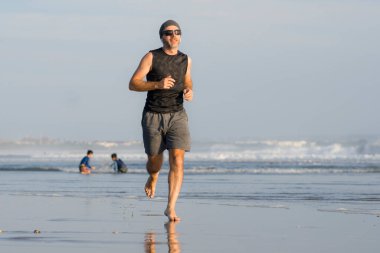 Açık hava koşusu antrenmanı. Genç çekici ve atletik koşucu. Yaz aylarında güzel plajlarda koşuyor. 