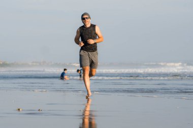 Açık hava koşusu antrenmanı. Genç çekici ve atletik koşucu. Yaz aylarında güzel plajlarda koşuyor. 