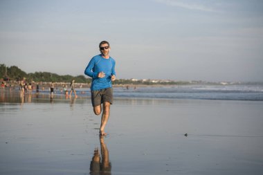 Açık hava koşusu antrenmanı. Genç çekici ve atletik koşucu. Yaz aylarında güzel plajlarda koşuyor. 