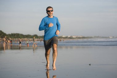 Açık hava koşusu antrenmanı. Genç çekici ve atletik koşucu. Yaz aylarında güzel plajlarda koşuyor. 