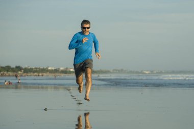 Açık hava koşusu antrenmanı. Genç çekici ve atletik koşucu. Yaz aylarında güzel plajlarda koşuyor. 