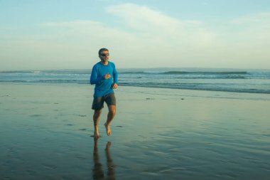 Açık hava koşusu antrenmanı. Genç çekici ve atletik koşucu. Yaz aylarında güzel plajlarda koşuyor. 