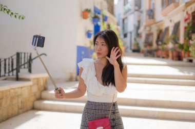 Asyalı kız sokakta kendi portresini çekiyor. Genç mutlu ve çekici Asyalı kadın İspanya 'da Sevilla' yı ziyaret ediyor. Selfie çekiyor.