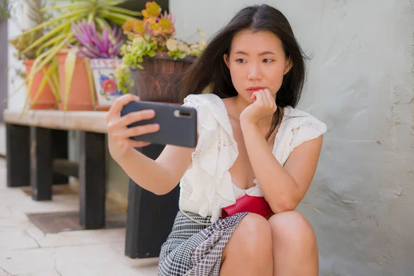 Asian girl taking self portrait on the street - young happy and attractive Asian Chinese woman visiting Seville in Spain taking selfie enjoying beautiful old city tour cheerful and relaxed