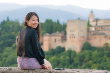 Avrupa 'da yaz tatili boyunca genç, güzel ve mutlu Asyalı Japon turist kadının hayat tarzı portresi. Neşeli bir şekilde Granada İspanya' da Alhambra 'nın güzel manzarasının tadını çıkarıyor.