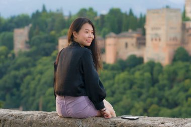 Avrupa 'da yaz tatili boyunca genç, güzel ve mutlu Asyalı Koreli turist kadının hayat tarzı portresi. Neşeli bir şekilde Granada İspanya' da Alhambra 'nın güzel manzarasının tadını çıkarıyor.