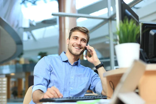 Усміхнений бізнесмен сидить і використовує мобільний телефон в офісі . — стокове фото