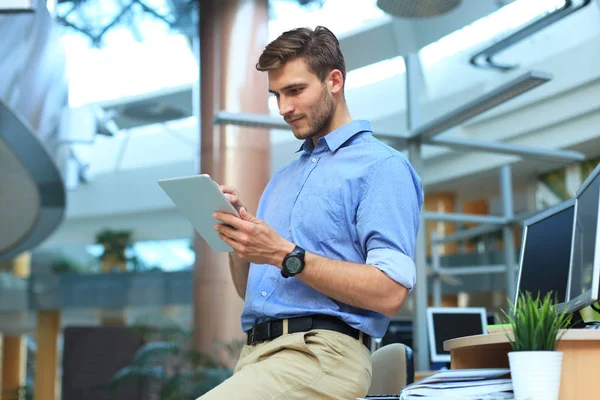 Jeune homme utilisant sa tablette dans le bureau. — Photo