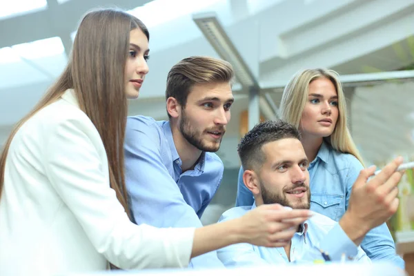 Grupp ungdomar i fritidskläder sitter på kontoret skrivbordet och diskutera något medan du tittar på Pc tillsammans. — Stockfoto