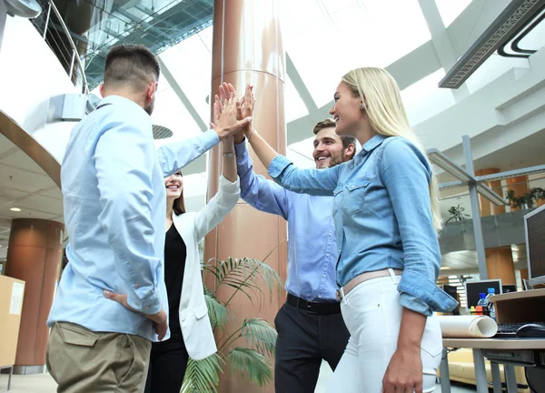 Happy young people standing in office and giving high five to their colleagues. — Stock Photo, Image
