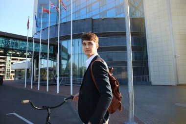 Kendine güvenen genç işadamı bisiklet ile şehirde sokakta yürüme