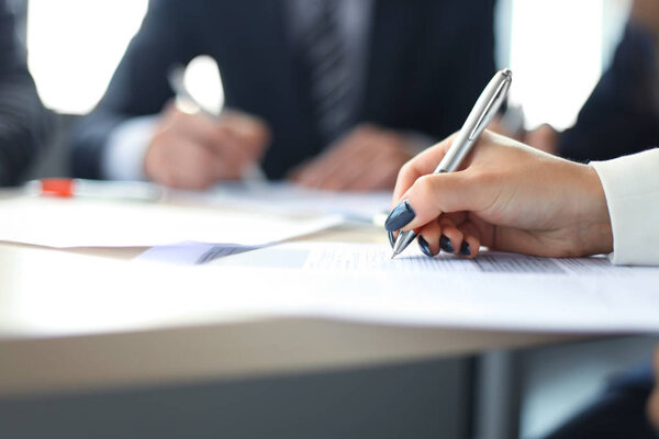 Businesswoman sitting in office, writing on documents