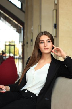 kanepede oturan ve kahve dükkanında smartphone kullanarak iş kadını