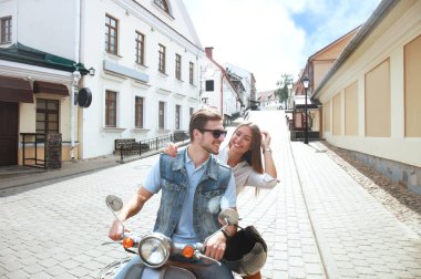 mutlu genç çift sürme scooter şehirde. Yakışıklı ve genç kadın seyahat. Macera ve tatil kavramı