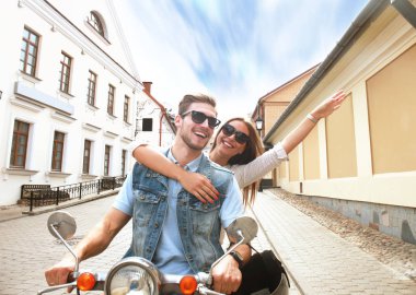 mutlu genç çift sürme scooter şehirde. Yakışıklı ve genç kadın seyahat. Macera ve tatil kavramı