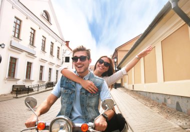 mutlu genç çift sürme scooter şehirde. Yakışıklı ve genç kadın seyahat. Macera ve tatil kavramı