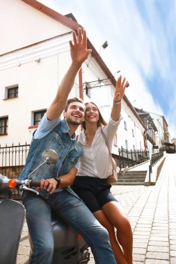 mutlu genç çift sürme scooter şehirde. Yakışıklı ve genç kadın seyahat. Macera ve tatil kavramı