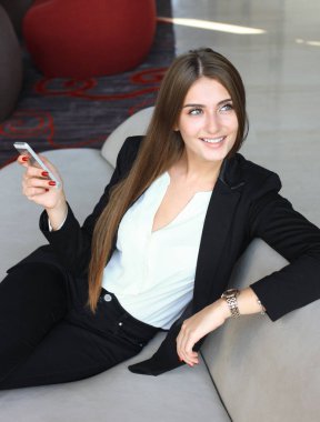 kanepede oturan ve kahve dükkanında smartphone kullanarak iş kadını