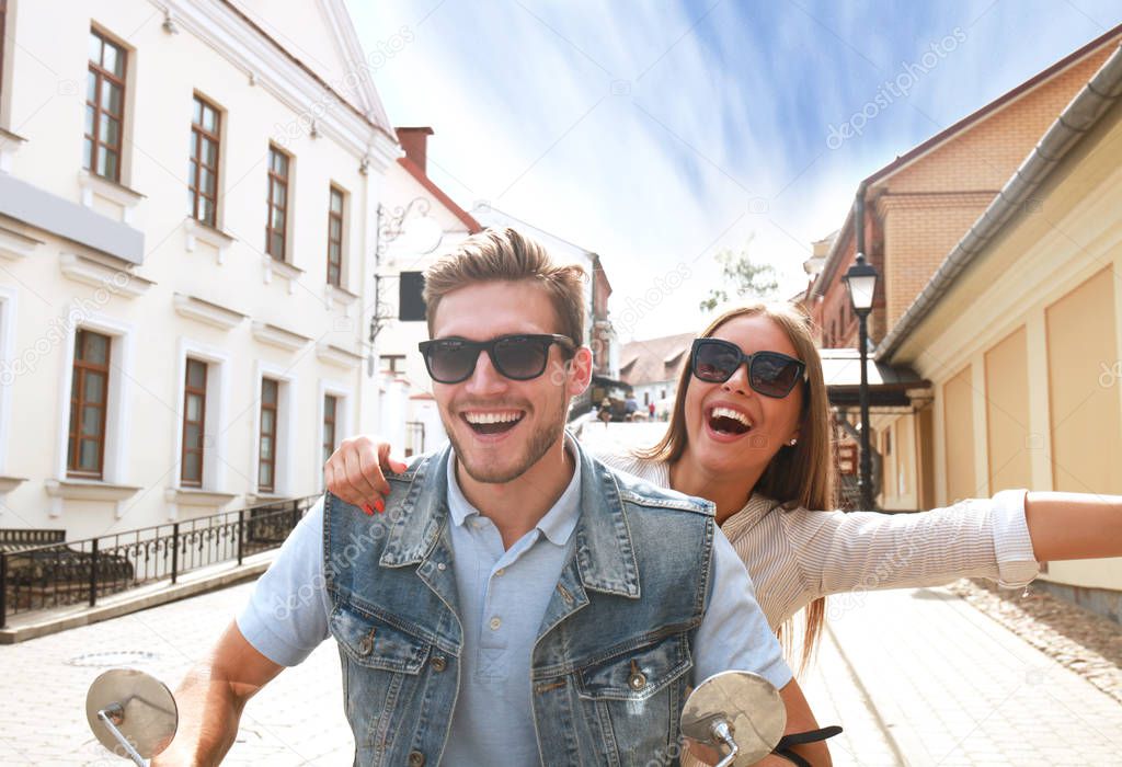happy young couple riding scooter in town. Handsome guy and young woman travel. Adventure and vacations concept