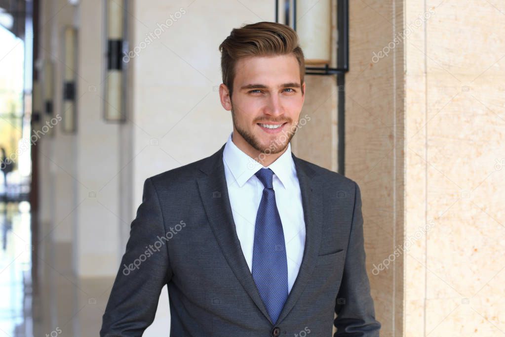 Portrait of happy young businessman standing in hotel lobby