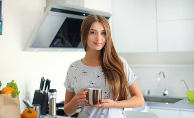 Mutfakta fincan çay ayakta tutan genç kadın