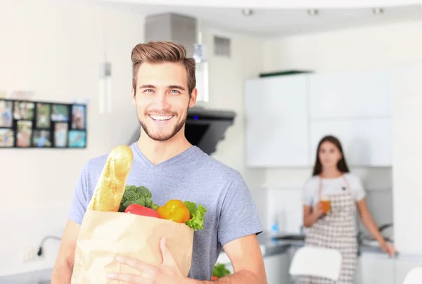 Young couple in the kitchen , man with a bag of groceries shopping