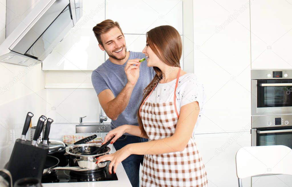 Portrait of happy young couple cooking together in the kitchen at home