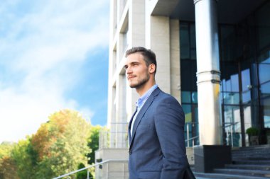 Takım elbiseli bir şehir binası dışında ayakta yakışıklı bir işadamı portresi