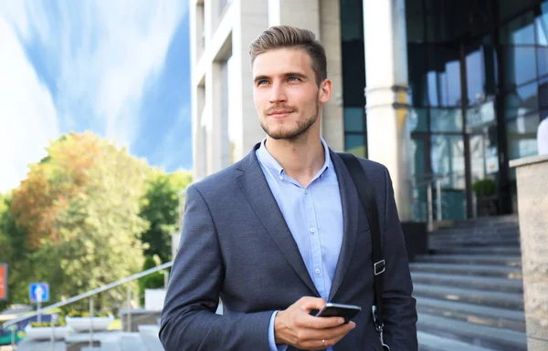 スマート フォンの携帯電話を使用して通りの歩行の若い都市のビジネスマン — ストック写真