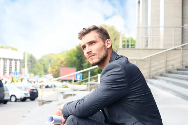 Gutaussehende Männliche Führungskraft Sitzt Auf Einer Treppe Vor Einem Gebäude — Stockfoto