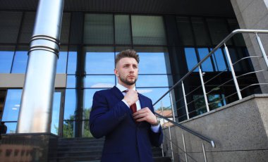 Takım elbise ayakta şehir Binası yakınındaki yakışıklı işadamı portresi