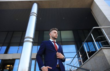 Takım elbise ayakta şehir Binası yakınındaki yakışıklı işadamı portresi